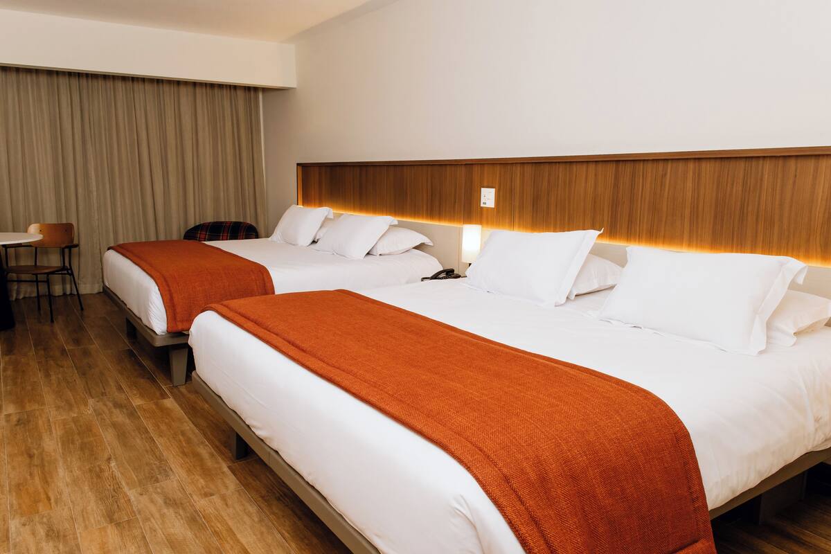 Ein Hotelzimmer mit zwei Betten, einem Holzkopfstück, einem Schreibtisch und einem Stuhl.