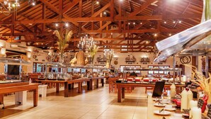 Una amplia cafetería con mesas y bancos de madera, una variedad de alimentos en exhibición y un techo alto con vigas a la vista.