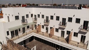 A multi-story building with balconies, a rooftop terrace with solar panels, and a courtyard area. - Hotel Casa de Oración San José (Puebla)