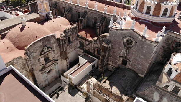 An aerial view of a historic building with multiple levels, including a rooftop terrace with a white railing. - Hotel Casa de Oración San José (Puebla)