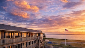 A waterfront building with a balcony, an American flag, and a view of the water. - Mariner's Point Resort (Falmouth)