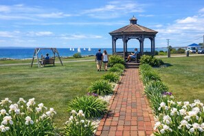 A gazebo, a swing set, and a pathway lined with flowers leading to the sea. - Mariner's Point Resort (Falmouth)