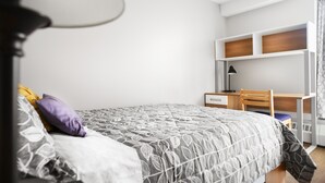 A bedroom with a bed, a desk, and a chair.