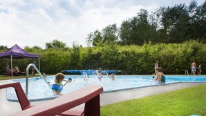 A swimming pool area with a slide, a tent, and a grassy area.