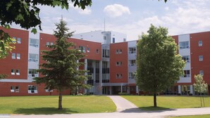A multi-story building with a red brick facade, large windows, and a central entrance.