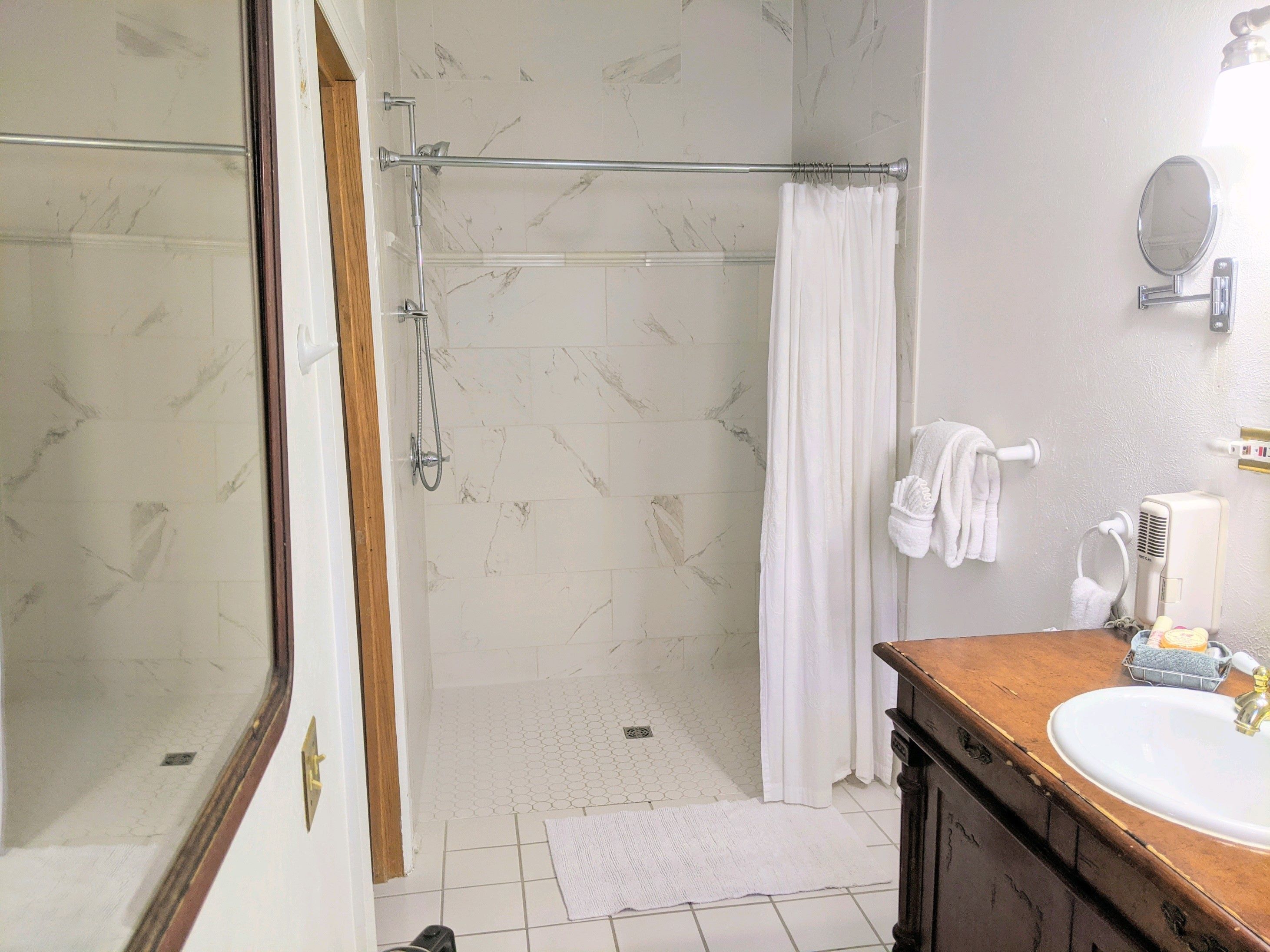 A bathroom with a shower, a sink, and a mirror.