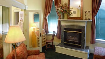 A living room with a fireplace, a lamp, a chair, and a dresser.