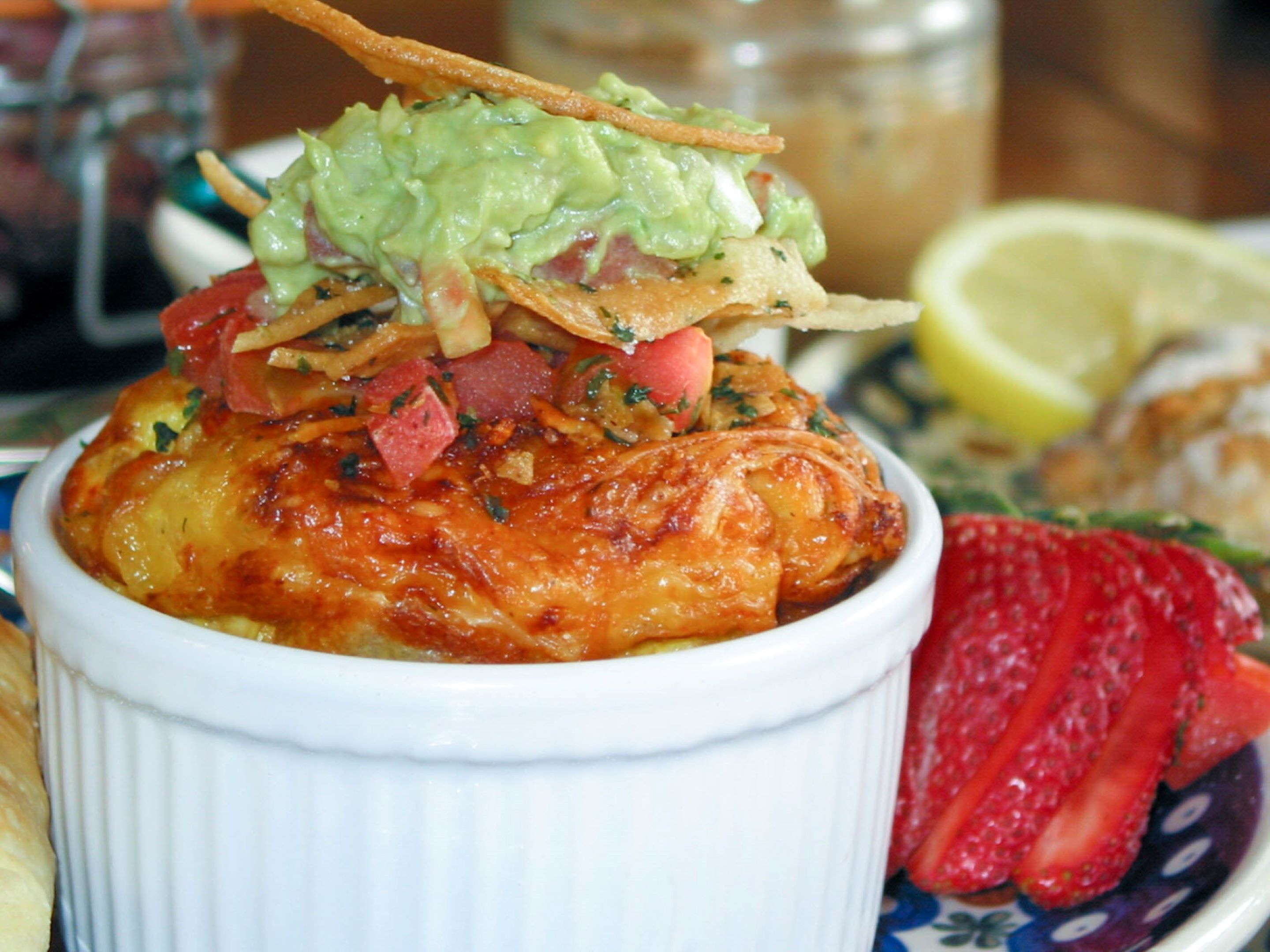 A bowl of food with a crispy topping, garnished with herbs and a slice of lemon.