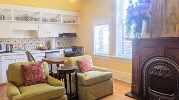 A cozy living room with a fireplace, a dining area, and a kitchen with white cabinets and patterned tiles.