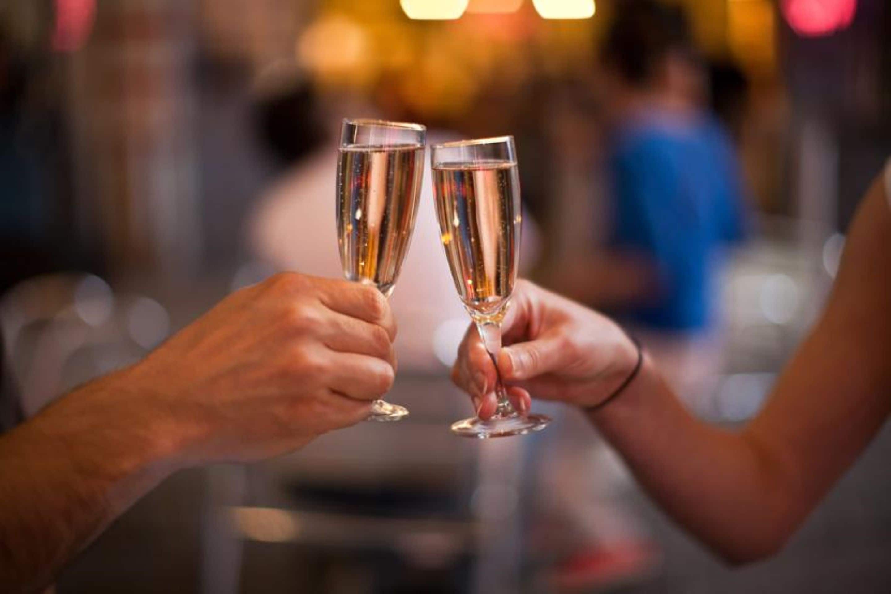 To hænder holder champagneglas.