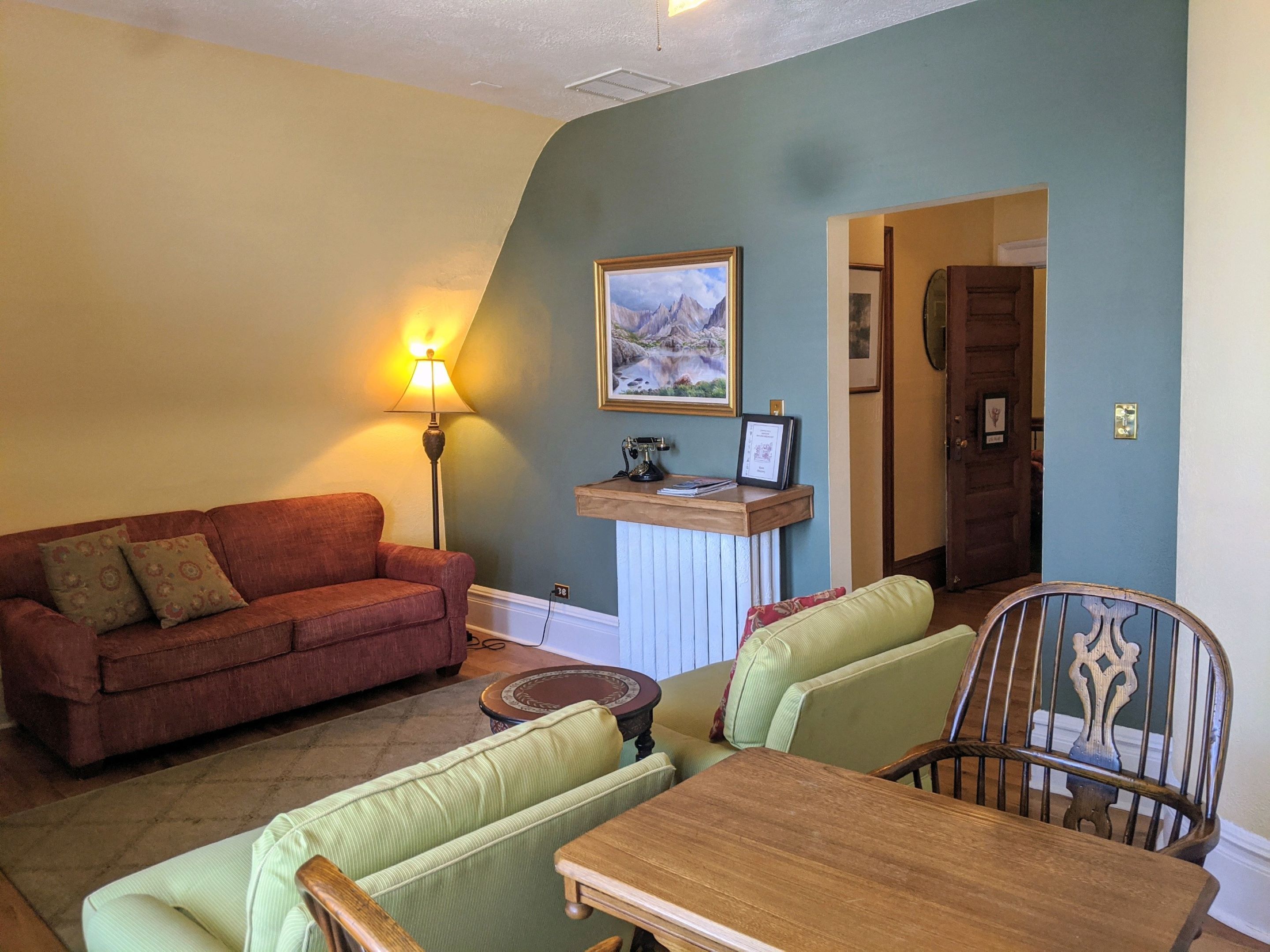 A living room with a red sofa, a green sofa, a wooden table, and a lamp.
