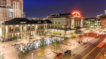 A historic building with a prominent neon sign, outdoor seating, and a well-lit plaza.