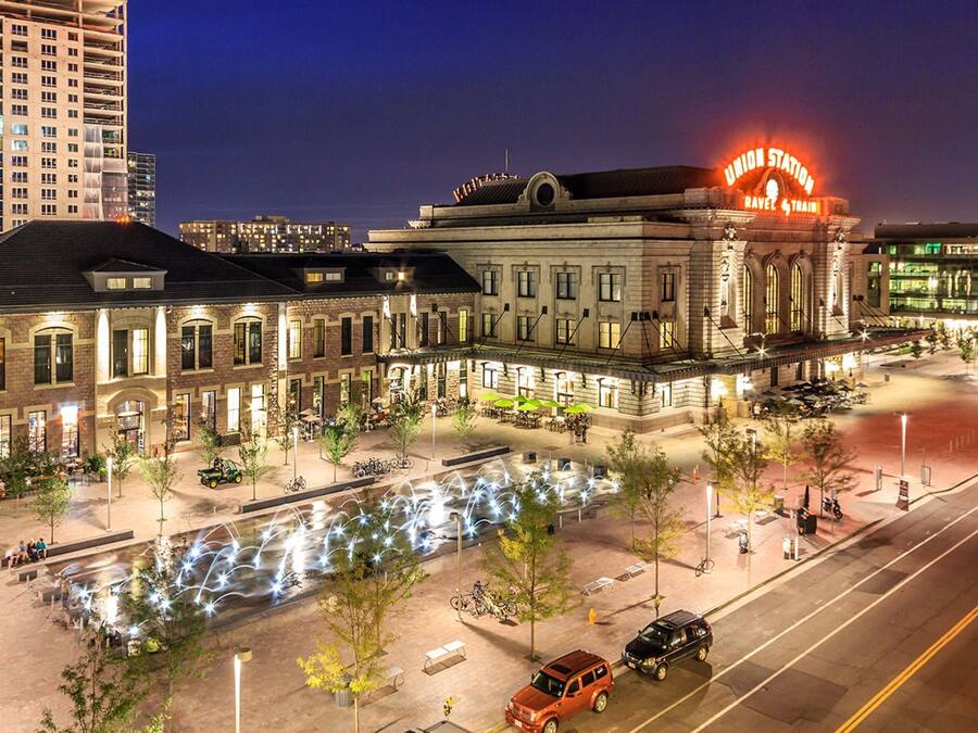 A historic building with a prominent neon sign, outdoor seating, and a well-lit plaza.