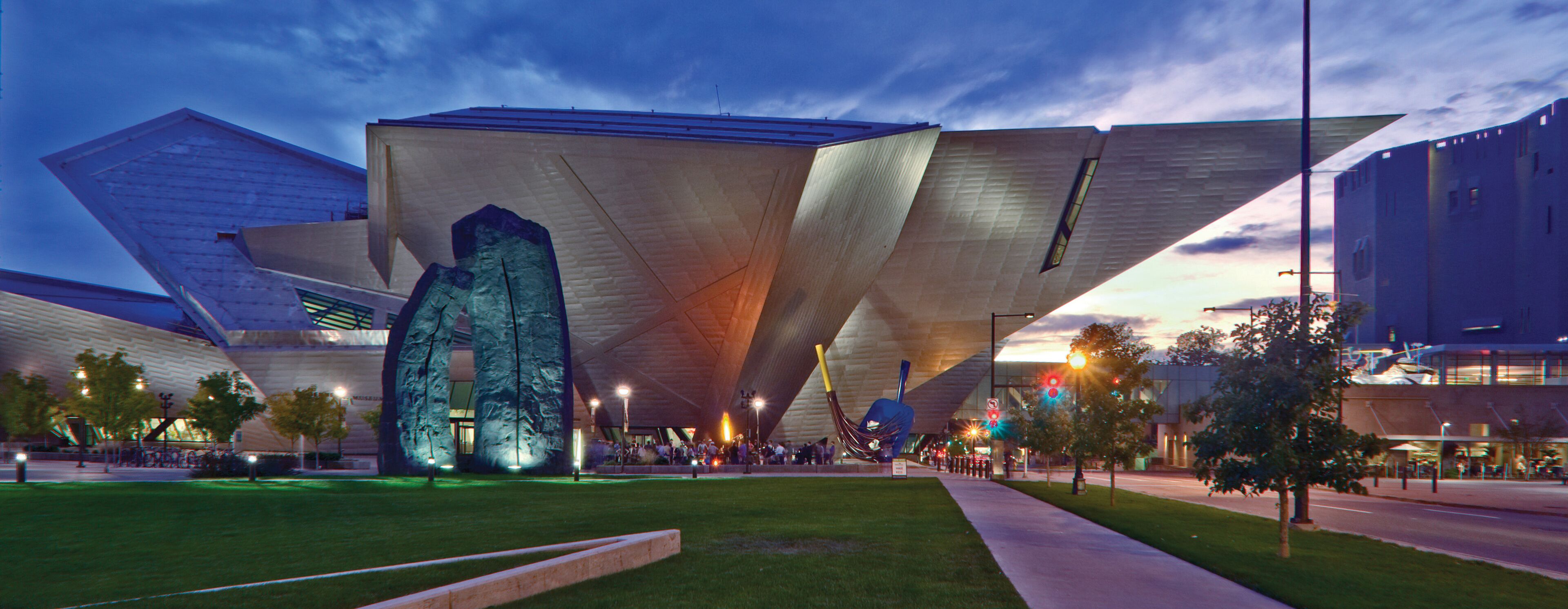 A modern building with a unique geometric design, featuring large, angular structures and a central, illuminated sculpture.