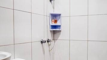 A small, tiled bathroom with a toilet, a shower, and a soap dispenser.