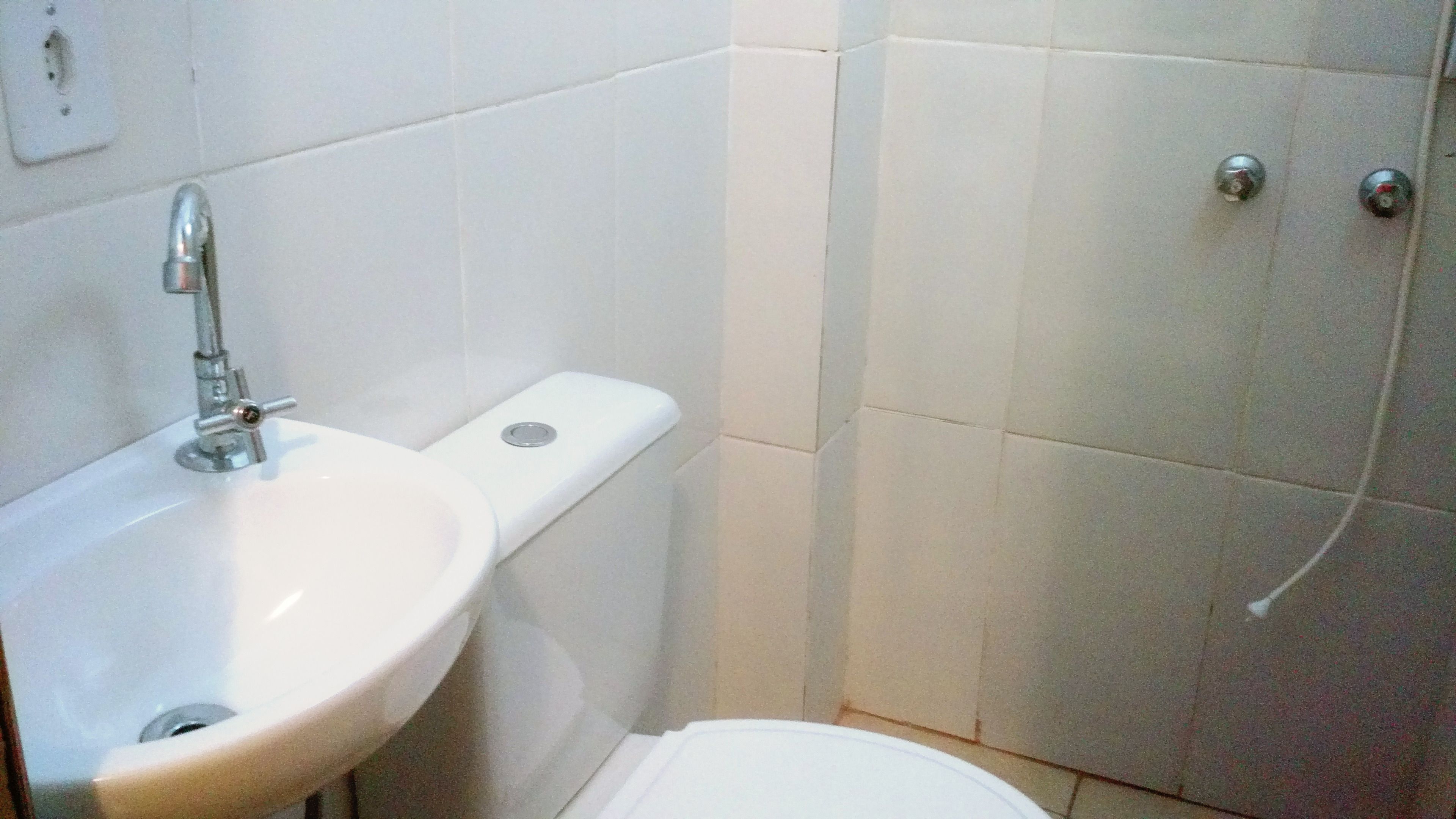 Een badkamer met een wit wastafel, toilet en douchehoek.