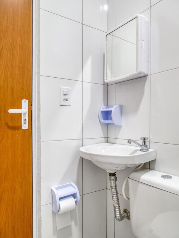 A bathroom with a white sink, a mirror, a toilet, and a paper towel dispenser. - Hotel Paulistano (São Paulo)