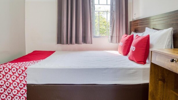 A bedroom with a bed, curtains, a window, and a wooden headboard. - Hotel Paulistano (São Paulo)