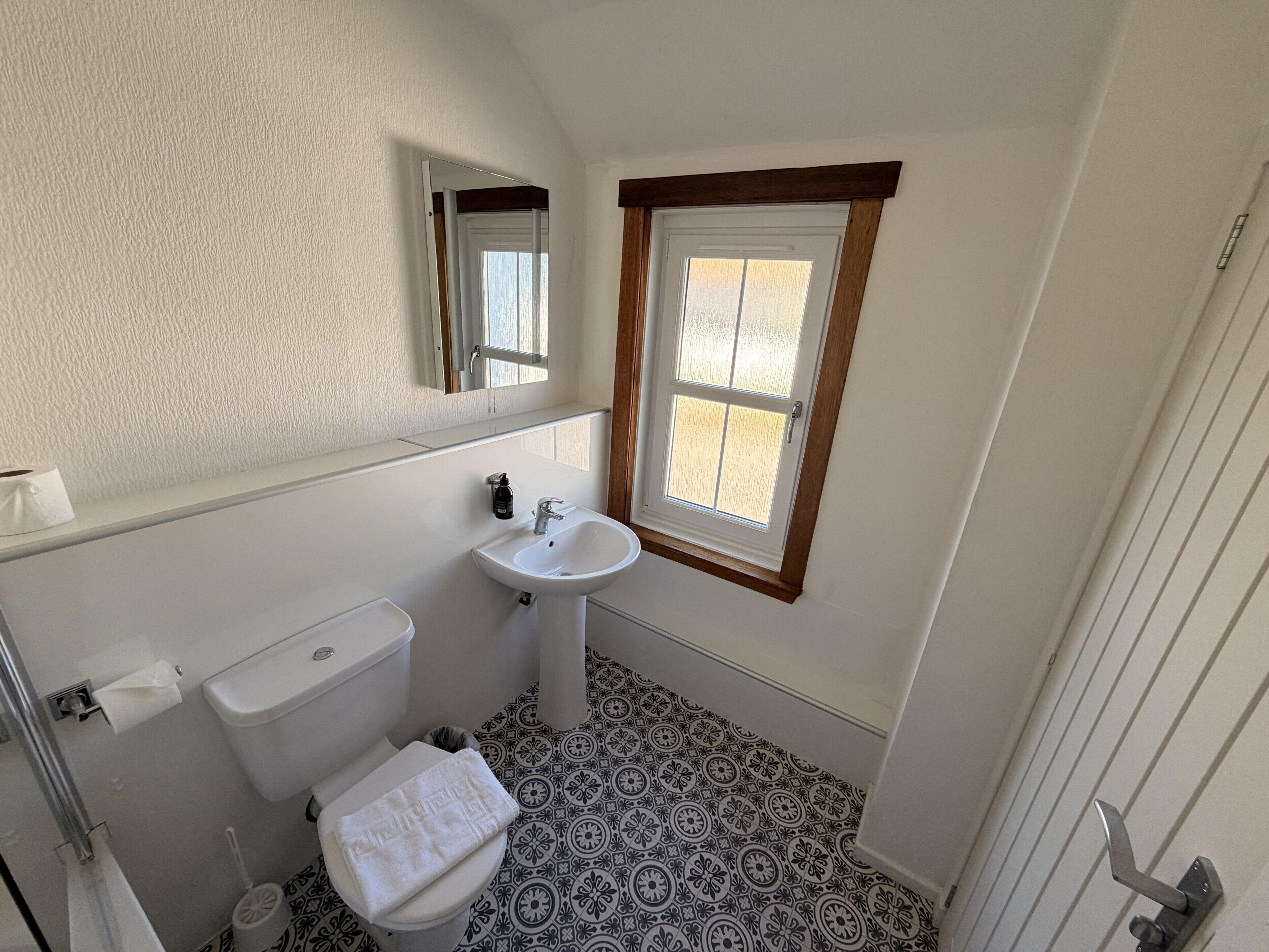 A bathroom with a toilet, sink, and window.