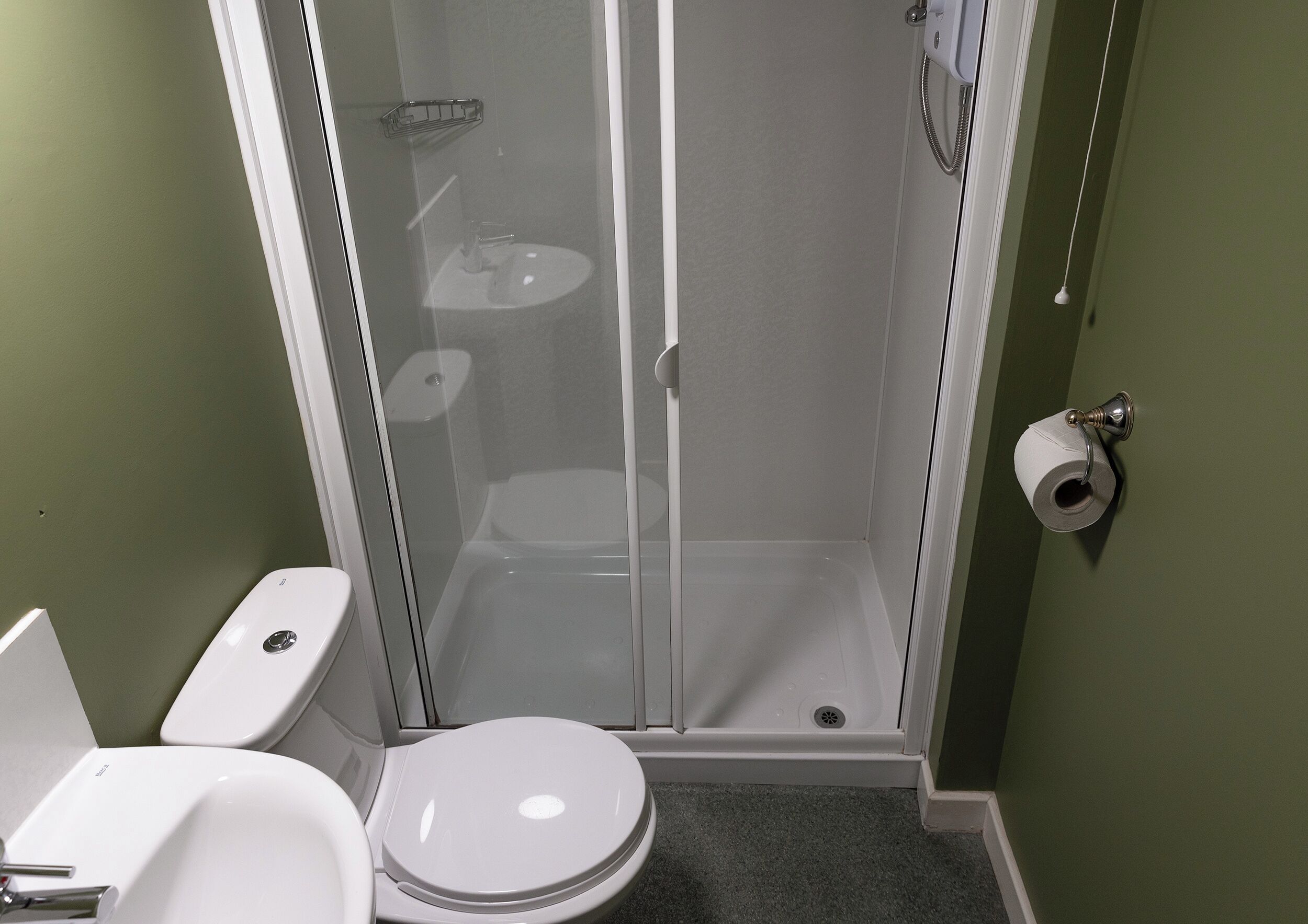A small bathroom with a toilet, sink, and shower stall.