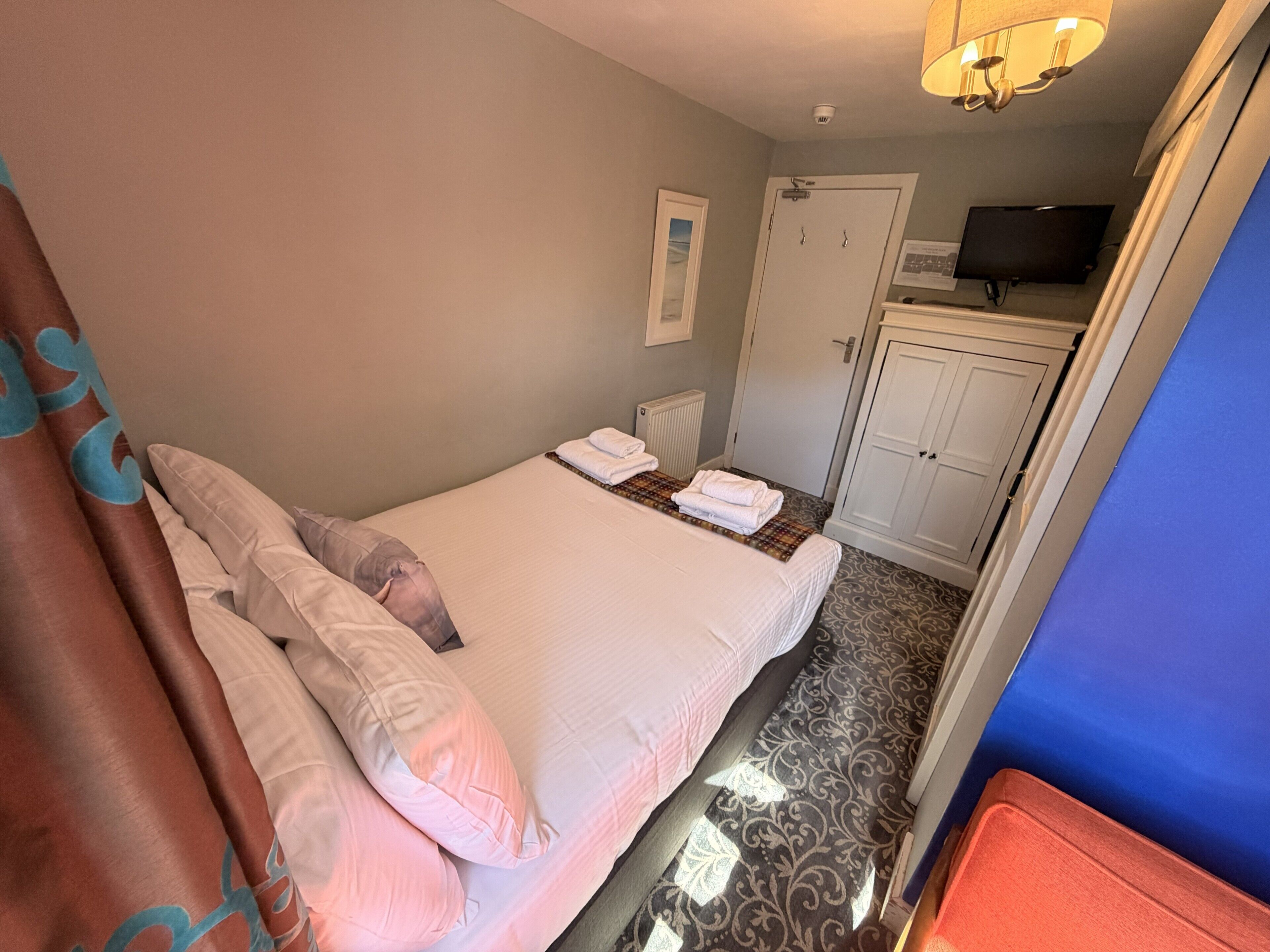 Une chambre d’hôtel comprenant un lit, une salle de bain, une télévision et une armoire.