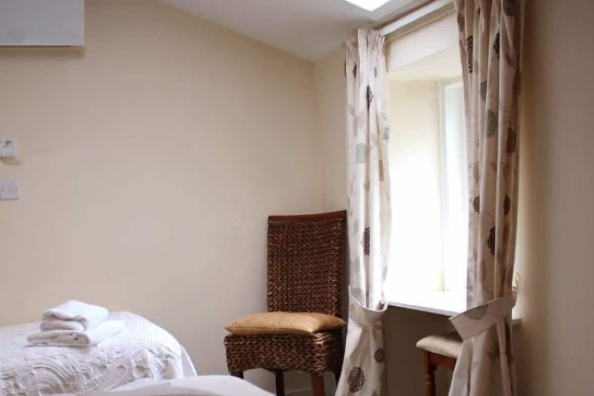 A hotel room with two beds, a chair, and a window with curtains.