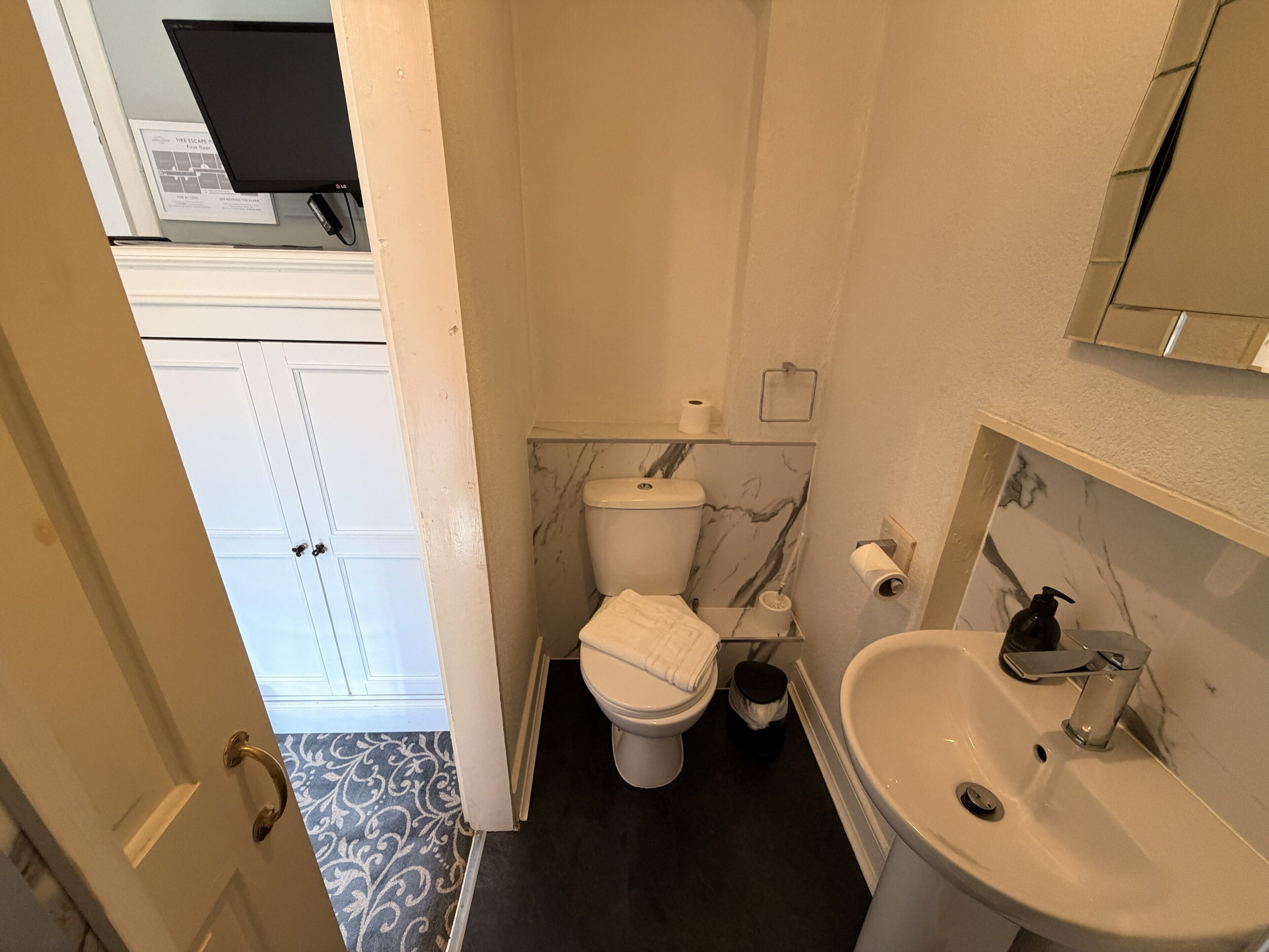Un baño pequeño con inodoro, lavabo y un cesto de basura.