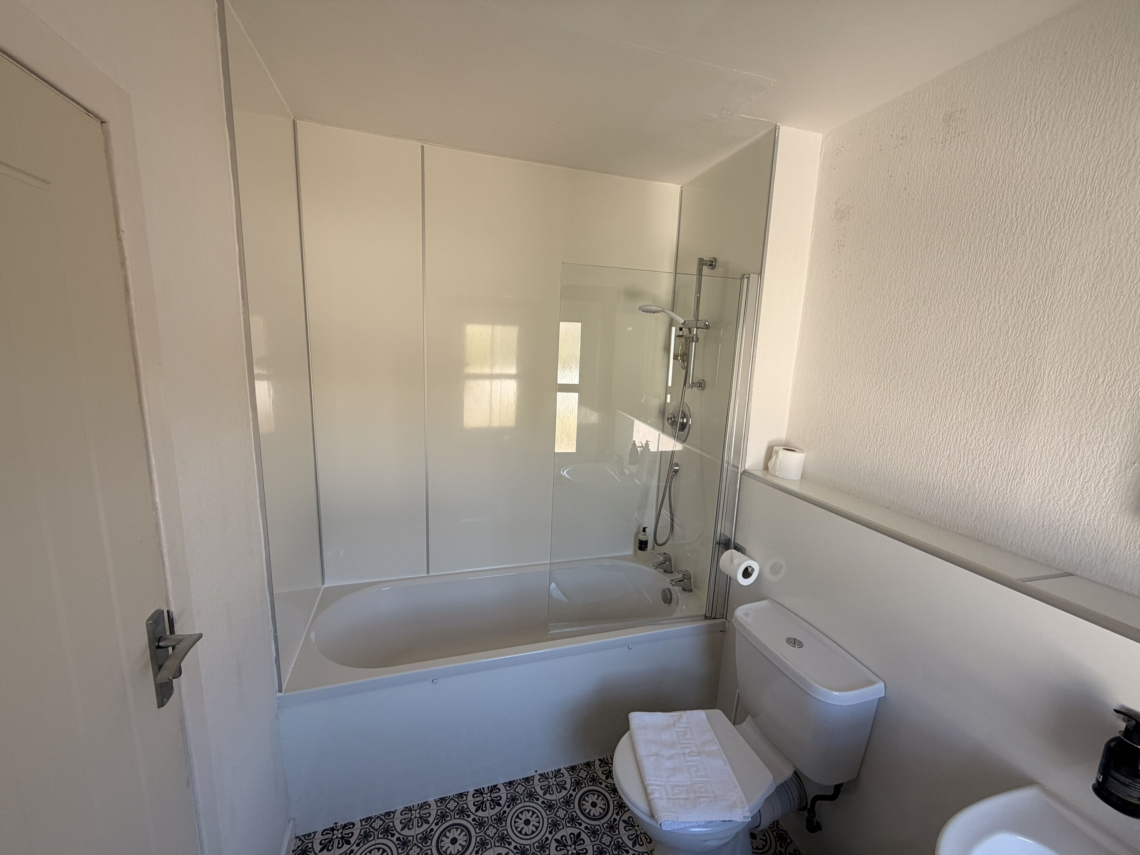 A bathroom with a bathtub, toilet, and a shower enclosure.