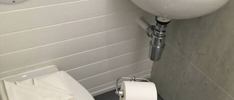 A bathroom with a white sink, toilet, and a towel on the floor.