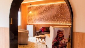 A cozy living room with a brick wall, a white sofa, a small round table, and a fluffy rug. - Hotel El Tambo 1 (Lima)