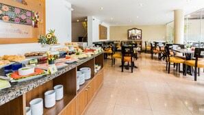 A buffet area with various food items and a seating area with yellow chairs. - Hotel El Tambo 1 (Lima)