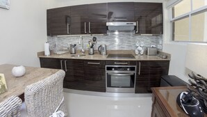 Una cucina moderna con mobili in legno scuro, elettrodomestici in acciaio inossidabile e una parete rivestita in piastrelle.