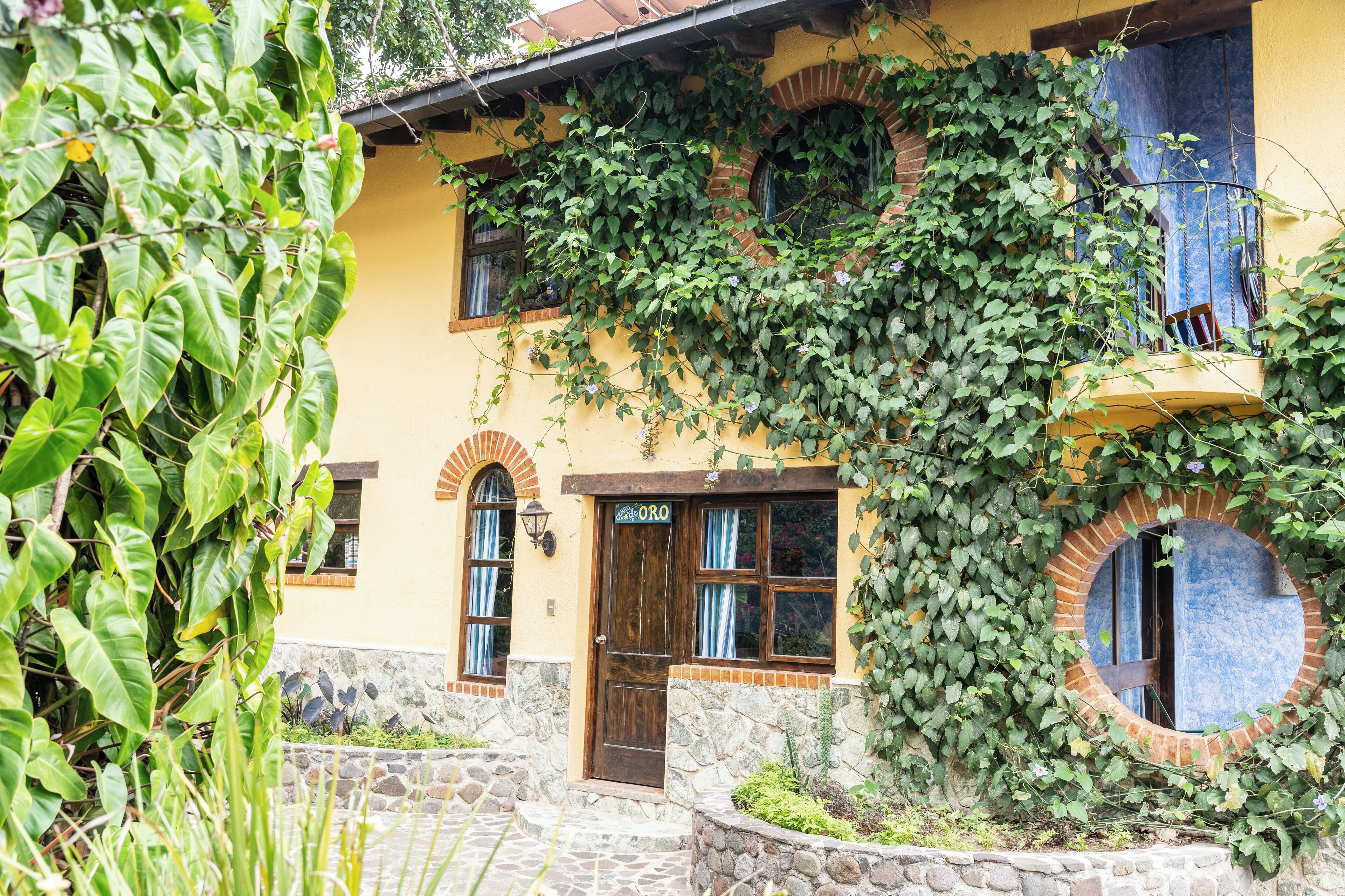 Un bâtiment à la façade jaune, avec des marches en pierre et une porte en bois portant l’inscription « Oro ».