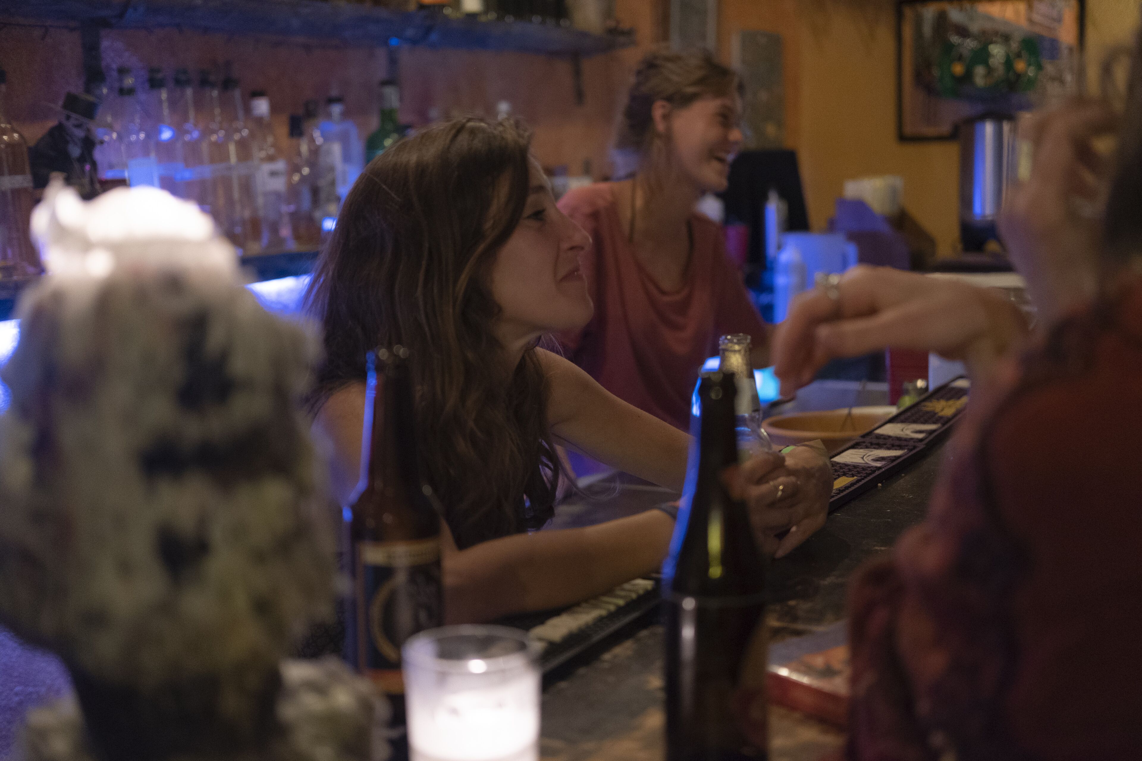 Una zona de bar con botellas y vasos sobre el mostrador.