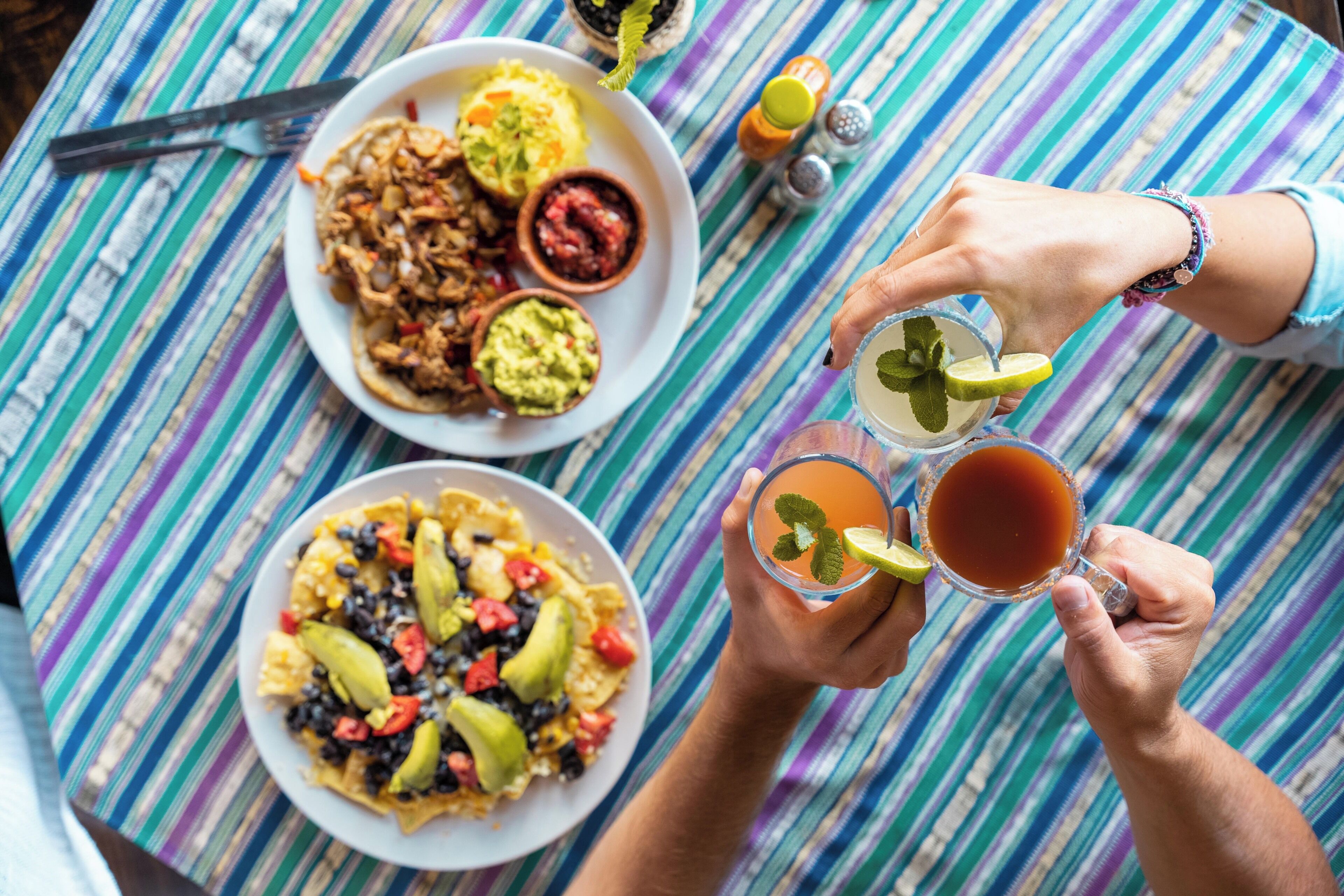 Uma mesa com dois pratos de comida, uma bebida e acompanhamentos.