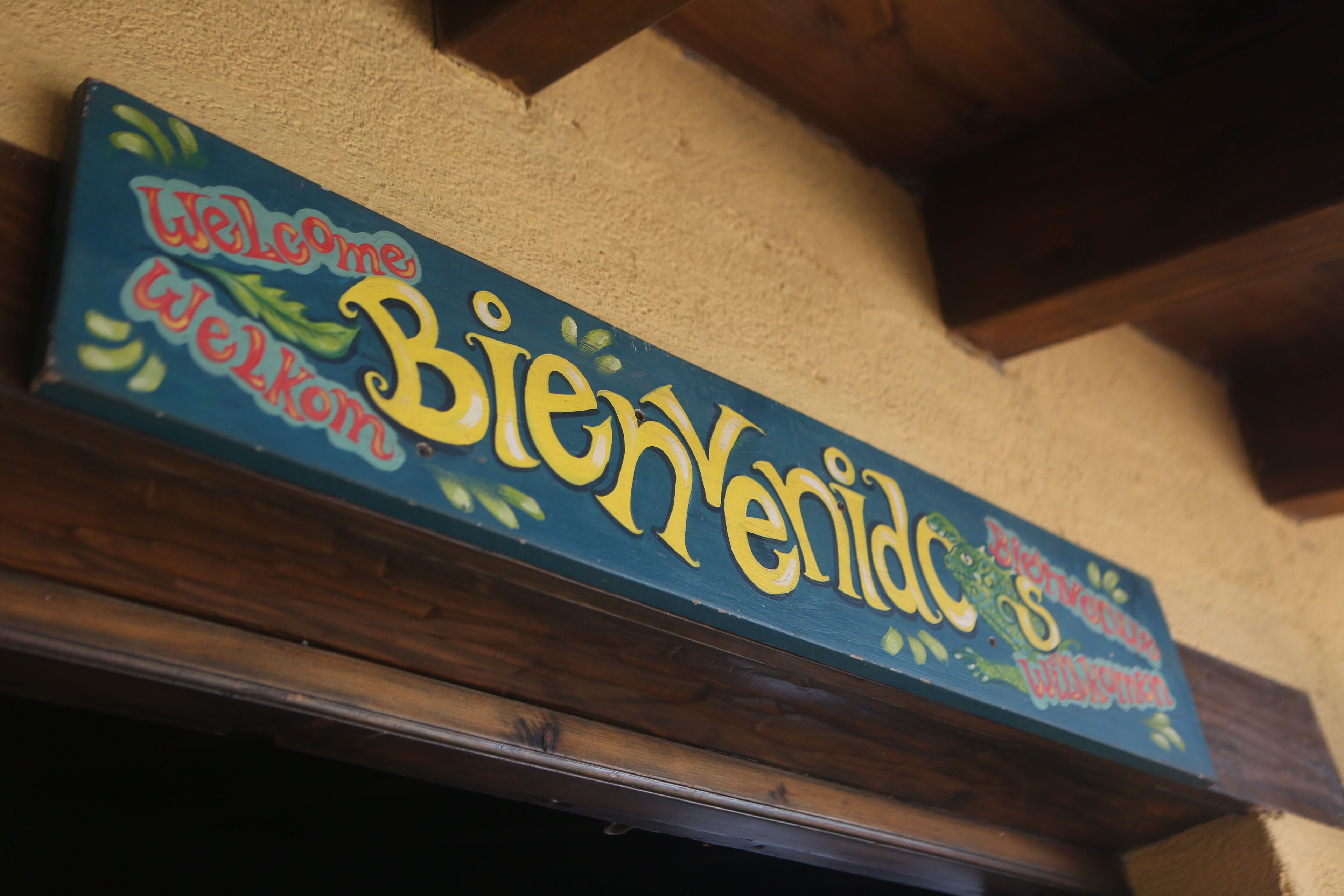 A wooden sign with the words "Welcome Bienvenidos" in multiple languages.