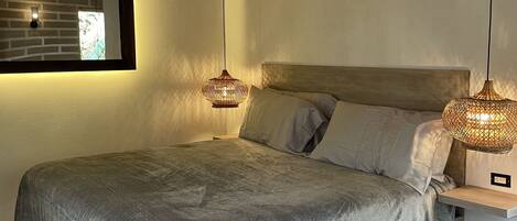 Ein Schlafzimmer mit einem Bett, Holzbalken, einer Hängeleuchte und einer Wandleuchte.