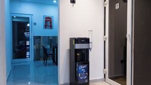 Een hotellobby met een waterdispenser, een brandblusser en een gesloten deur.