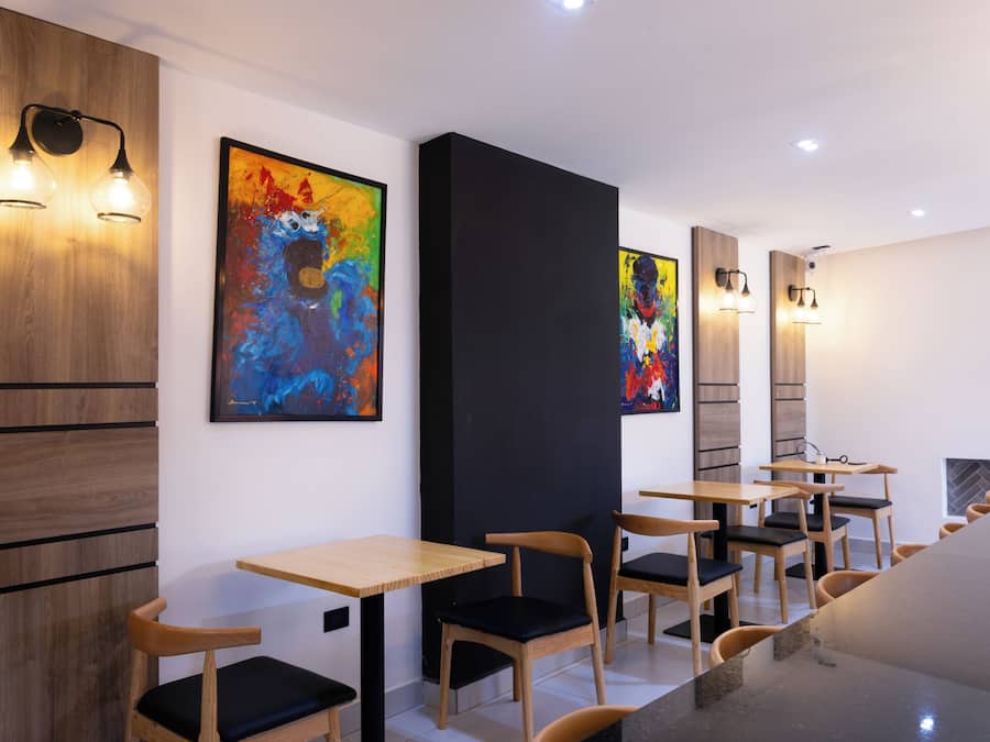A modern interior with wooden panel walls, abstract paintings, and simple wooden tables and chairs.