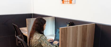 A workspace with a person seated at a desk, a poster on the wall, and a partition between workstations.
