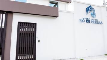 Um edifício moderno com fachada branca, um portão preto e uma placa com a inscrição 'MICRO HOTEL RIO DE MEDRAS'.