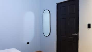 Una habitación con cama, puerta y espejo fijado a la pared.