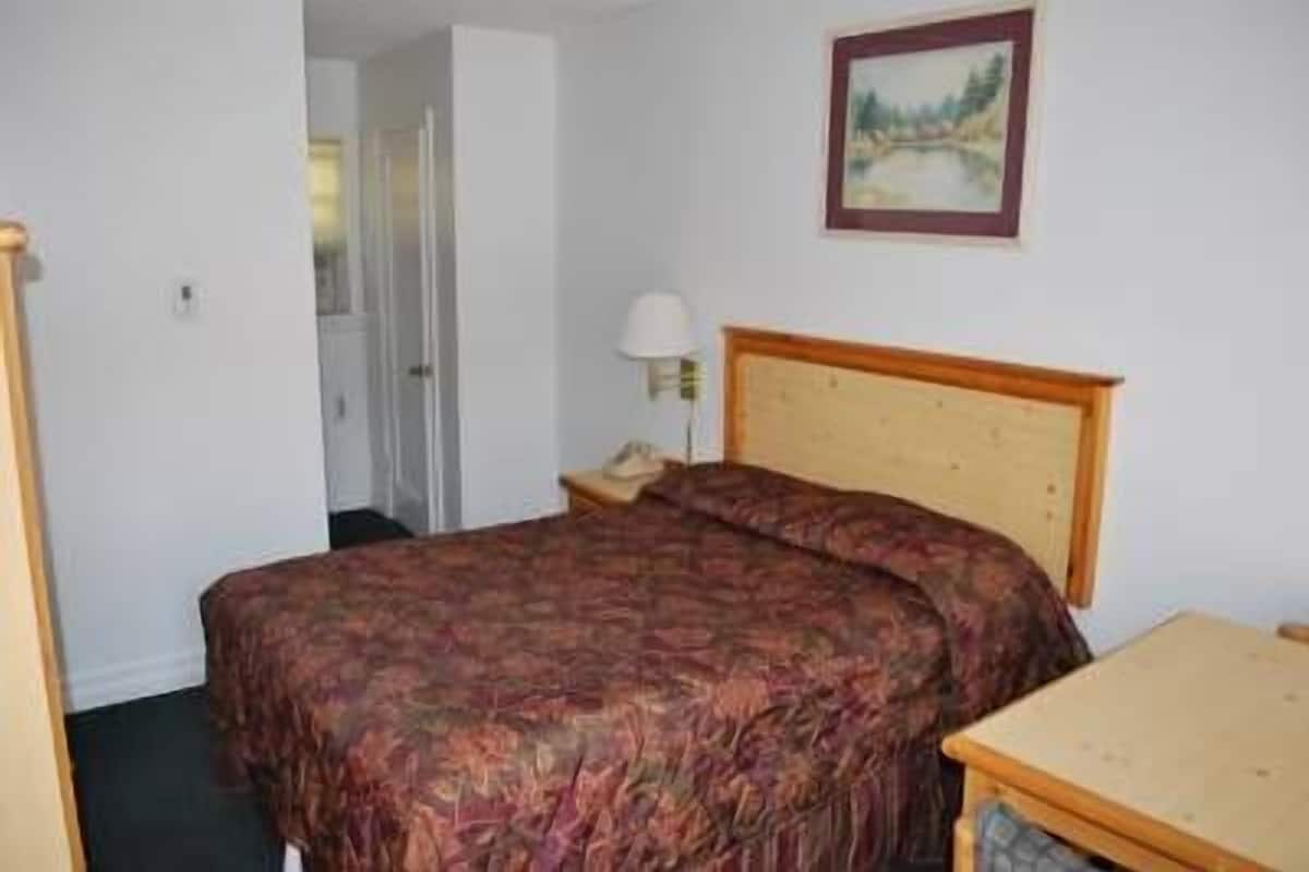 A bedroom with a bed, a nightstand, a lamp, and a painting on the wall.