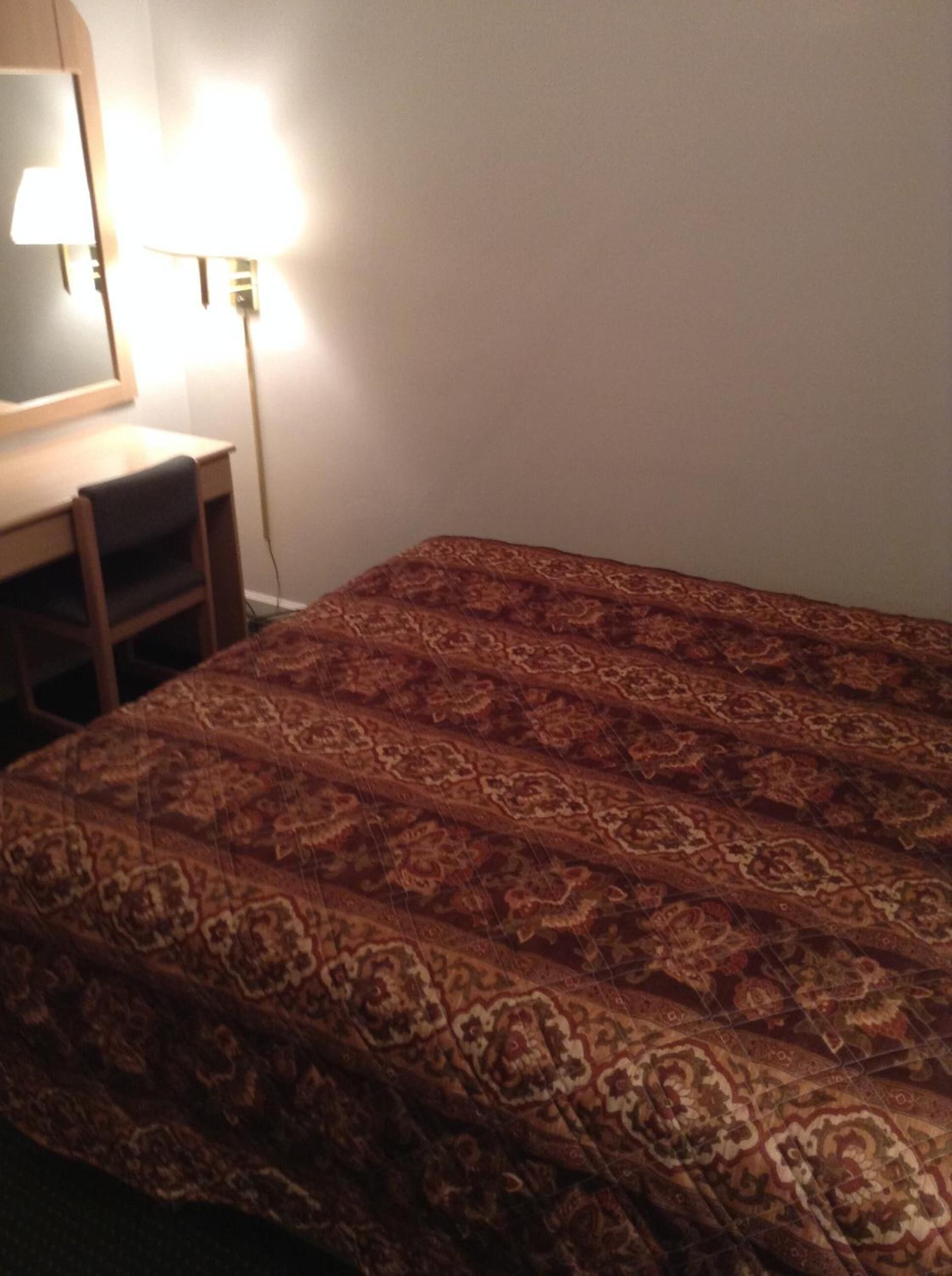 A room with a bed, a desk, and a lamp.