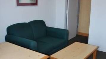 Une pièce avec un canapé vert, une table en bois et une chaise à motifs.