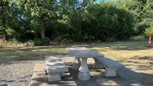 A stone picnic table with benches in a grassy outdoor area. - Boomtown Inn (Drumright)