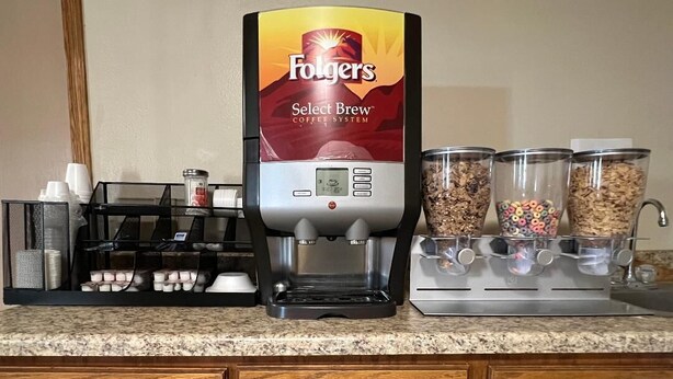 A coffee maker, a coffee machine, and containers of coffee grounds and creamer on a kitchen counter. - Boomtown Inn (Drumright)