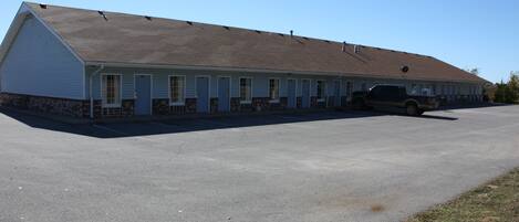 Un motel composé d’un bâtiment d’un seul étage, d’un parking et d’un VUS garé.