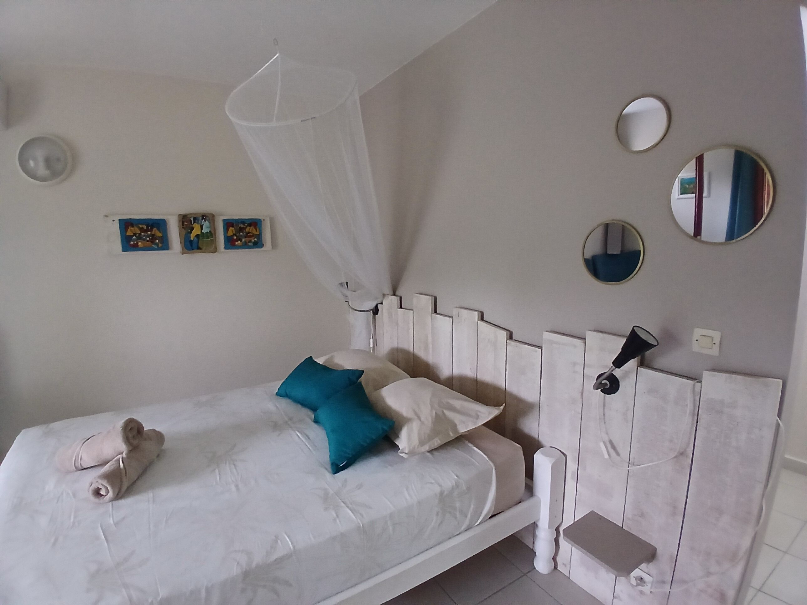A bed with a canopy, a bedside table, and wall-mounted mirrors.