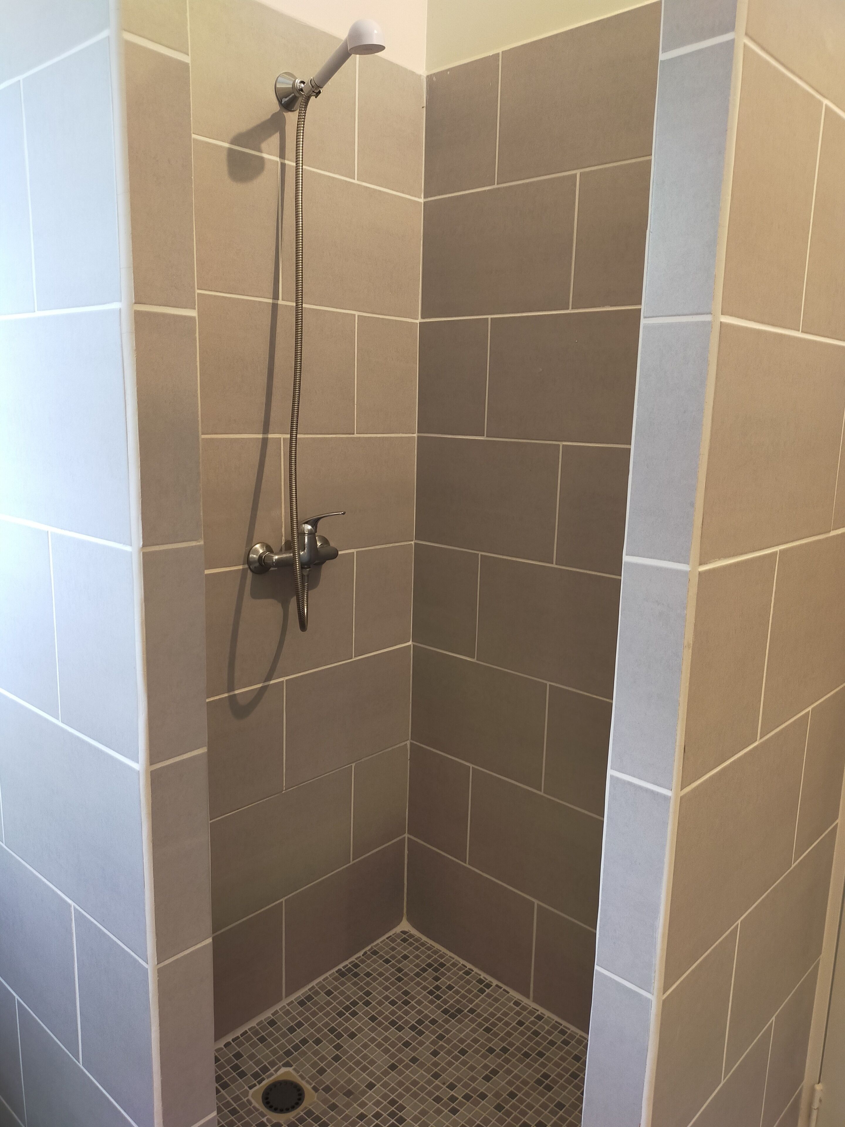 A shower area with tiled walls and a drain.